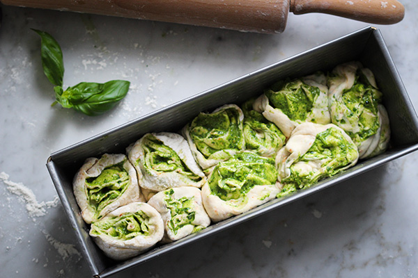 Gerollten Teig mit Basilikumpesto in die Kastenform schichten