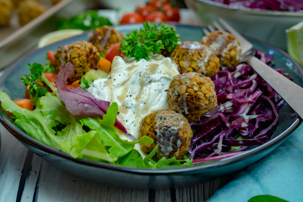 Bunte Bowl mit Salat, Couscous, Hackbällchen und Tahin-Sauce